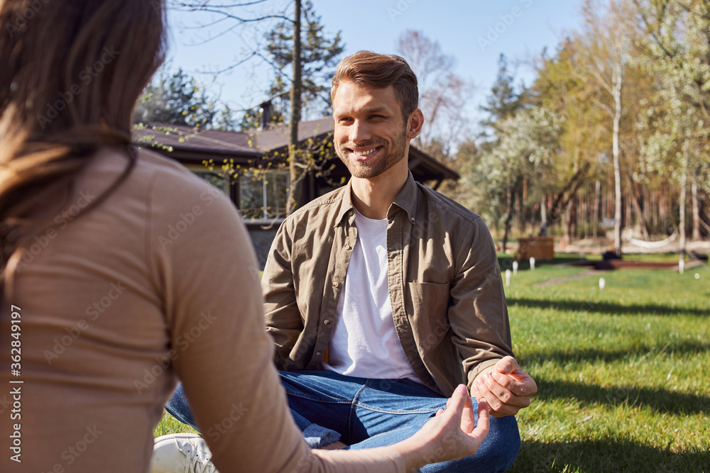 Smiling man sitting in lotus position and looking at his girlfriend