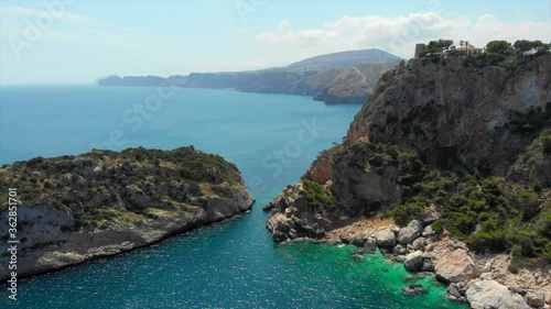 Aerial drone point of view picturesque turquoise bay green water lagoon of Mediterranean Sea rocky coastline, idyllic Ambolo beach for snorkelling and swimming, summer hot day. Costa Blanca, Spain photo