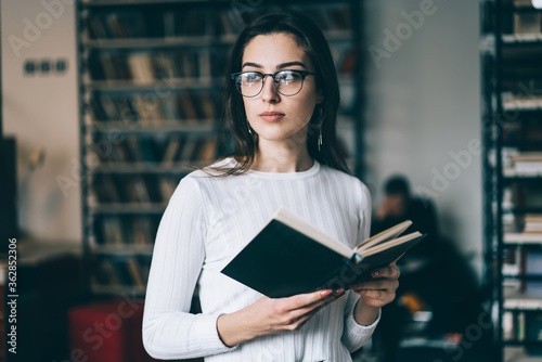 Smart woman reading book in library