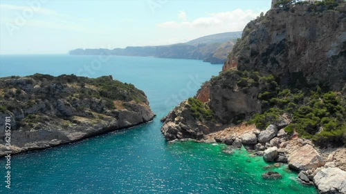 Aerial drone point of view picturesque turquoise bay green water lagoon of Mediterranean Sea rocky coastline, idyllic Ambolo beach for snorkelling and swimming, summer hot day. Costa Blanca, Spain photo