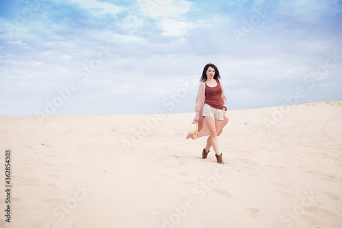 girl in desert walk with dark hair shorts, sand and blu sky background