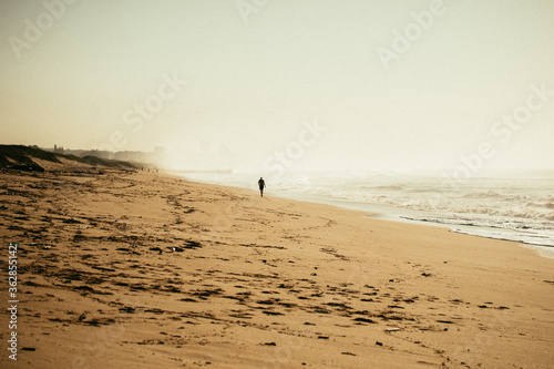 Person Walking Along the Beach at Sunrise