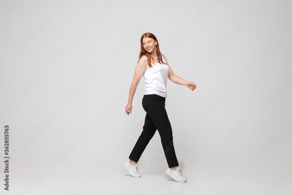 Coming confident. Young woman in casual wear on white background. Bodypositive character, feminism, loving herself, beauty concept. Plus size businesswoman during paperwork. Inclusion, diversity.