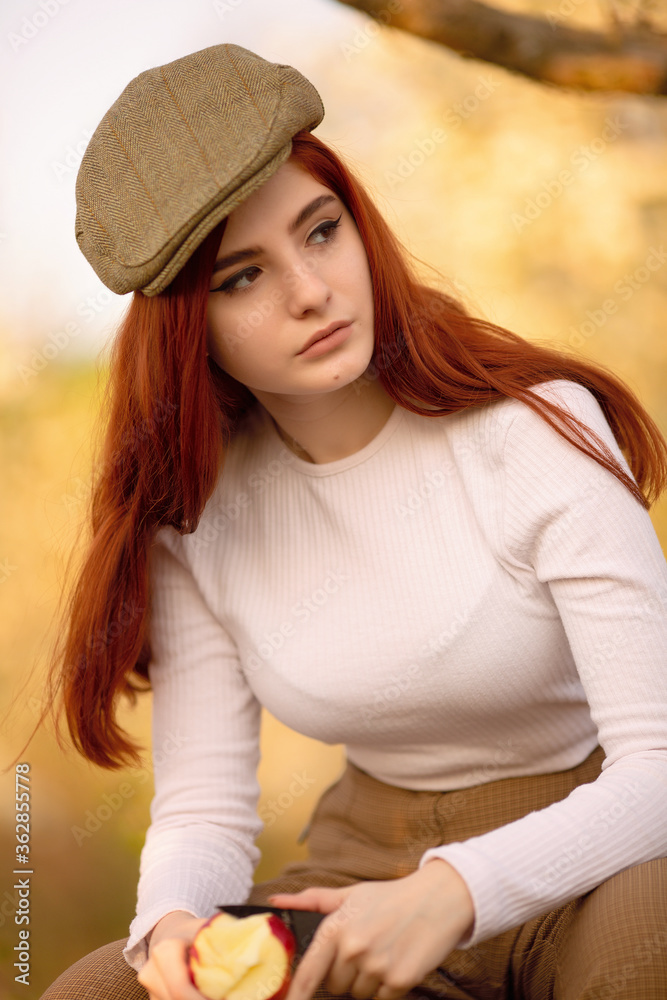 Fototapeta premium young beautiful red hair stylish girl seating on the boxes in apple tree garden, pants and white turtleneck, natural background