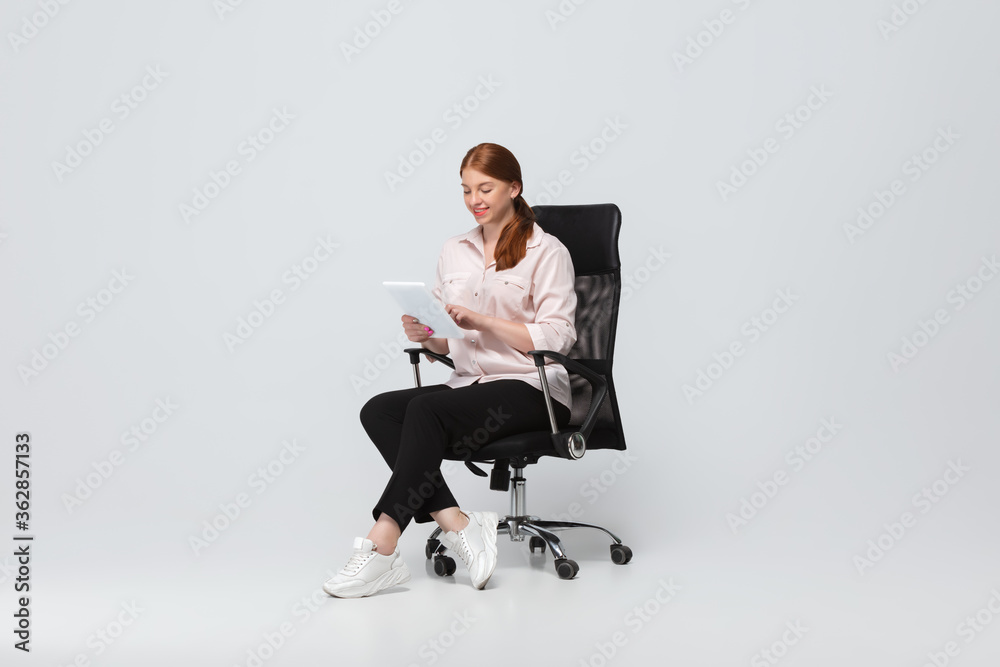 Working with tablet. Young woman in casual wear on white background. Bodypositive character, feminism, loving herself, beauty concept. Plus size businesswoman during paperwork. Inclusion, diversity. Working with tablet. Young woman in casual wear on white background. Bodypositive character, feminism, loving herself, beauty concept. Plus size businesswoman during paperwork. Inclusion, diversity.