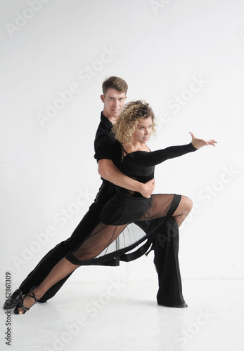 Beautiful couple in stylish dark costumes dancing ballroom dances