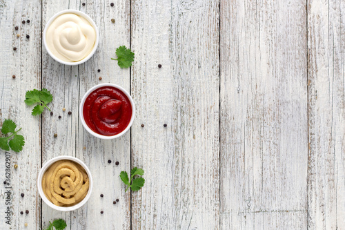 Set of various sauces with spices on white wooden background. Mayonnaise ketchup mustard.