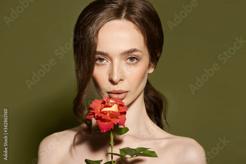 Beauty face of young woman with flower. Beauty treatment concept. Portrait of young woman with rose on green background.