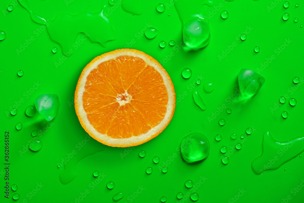 Fresh juicy slice of orange on bright green background covered with water drops Fresh juicy slice of orange on bright green background covered with water drops