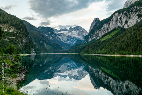 Sunny sunset colorful summer alpine view. Peaceful mountain lake with clear transparent water and reflections. Gosauseen or Vorderer Gosausee lake Salzkammergut Upper Austria. Dachstein summit glacier