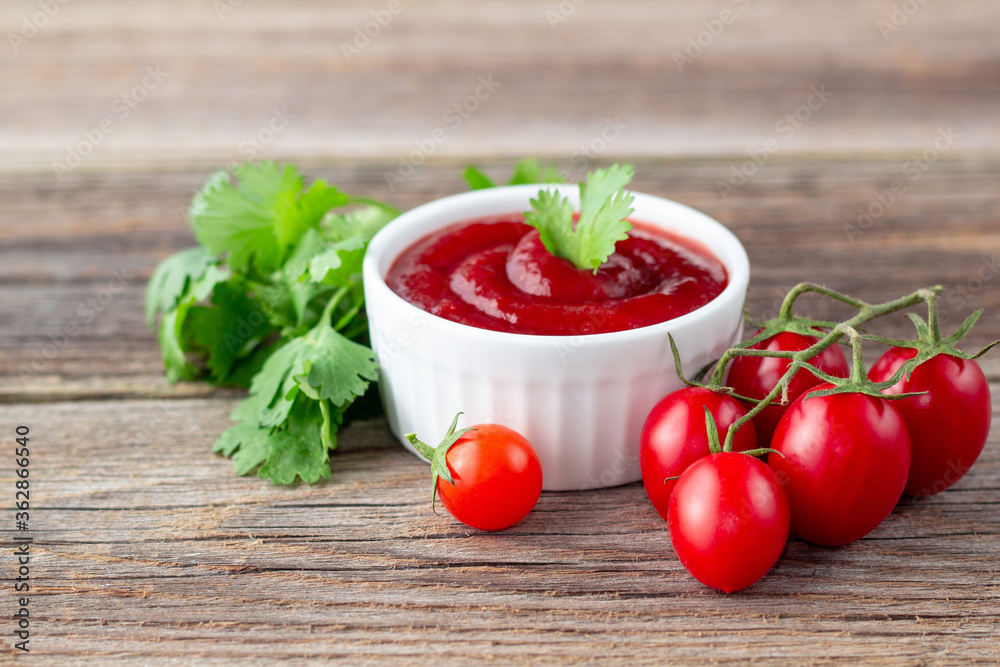 White bowl of tomato sauce with parsley and tomato. Ketchup on natural wooden background White bowl of tomato sauce with parsley and tomato. Ketchup on natural wooden background