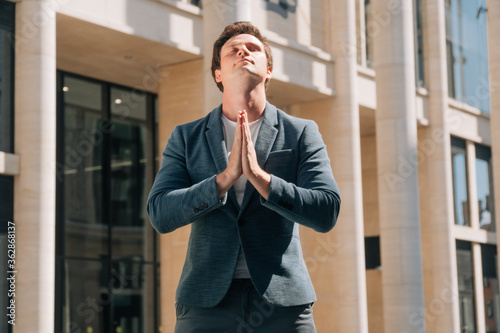 Portrait of a young businessman who prays at a special time. Request for help appealing to God