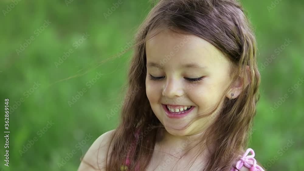 Close up of the face of a little girl trying to break some dry tree branches Close up of the face of a little girl trying to break some dry tree branches