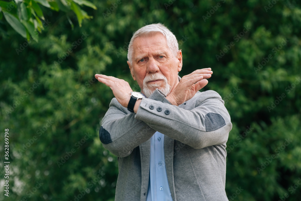 Fototapeta premium An elderly man in stylish clothes in nature. The concept of anger is a ban.