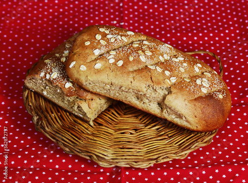 Loaves of whole wheat bread sprinkled with rolled oats on a wicker tray © IVAN