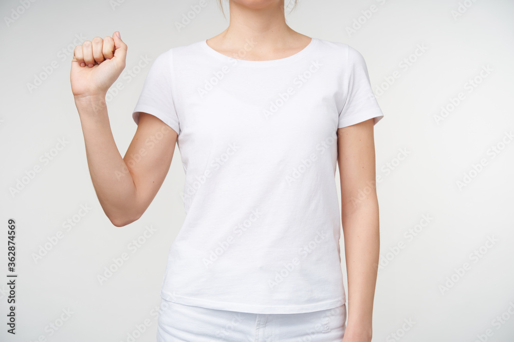 Horizontal shot of young female with nude manicure keeping fist raised while showing letter a on sign language, standing against white background Horizontal shot of young female with nude manicure keeping fist raised while showing letter a on sign language, standing against white background