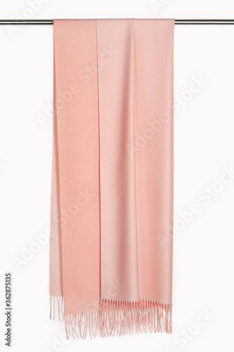 A cashmere pink scarf stole with fringe on hanger. White background, studio shot.