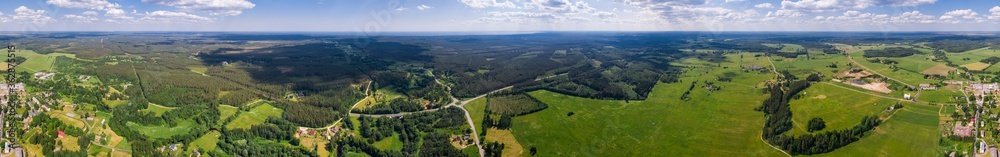 Aerial view of cloudy sunny day. Countryside surrounded by green fields, rivers and trees.