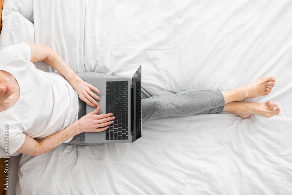 Naklejka premium Successful woman sitting in bed working on laptop