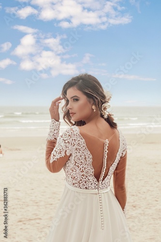 Beautiful bride in her wedding dress posing for photos on the beach. © Erica