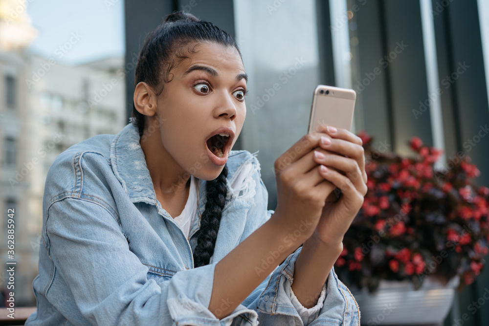 Excited African American Woman Using Mobile Phone Shopping Online Looking At Digital Screen Hipster Girl With Emotional Face Open Mouth Reading Breaking News Watching Movie Online Stock Photo Adobe Stock