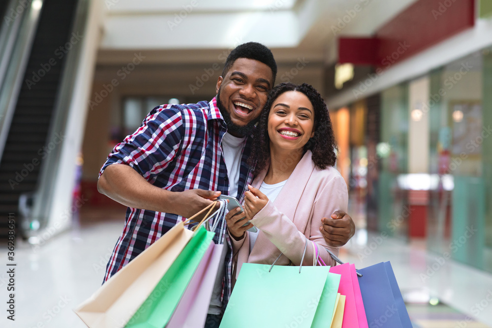 Seasonal Sales. African Spouses Posing In Mall With Lots Of Shopping Bags Seasonal Sales. African Spouses Posing In Mall With Lots Of Shopping Bags