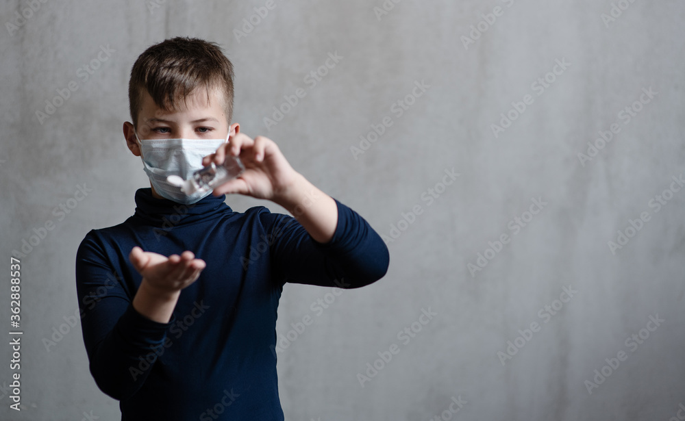 A boy in a medical mask shows how to properly handle his hands with a sanitizer. Hygiene rules during illness concept. Place for text. A boy in a medical mask shows how to properly handle his hands with a sanitizer. Hygiene rules during illness concept. Place for text.