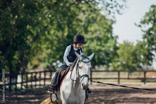 Little Girl in helmet Learning Horseback Riding. Instructor teaches kid Equestrian.