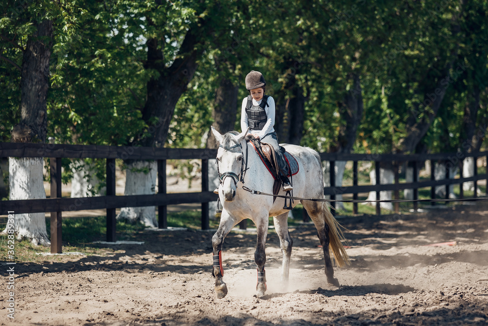 Little Girl in helmet Learning Horseback Riding. Instructor teaches kid Equestrian. Little Girl in helmet Learning Horseback Riding. Instructor teaches kid Equestrian.