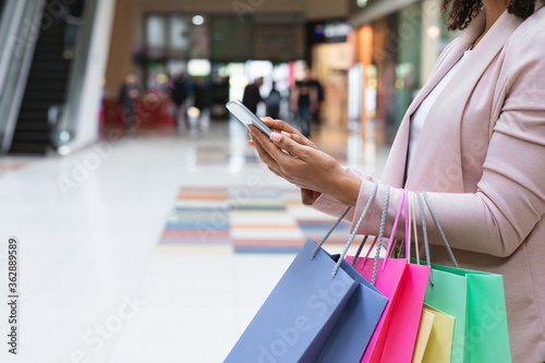 Cashback Bonus. Woman With Shopper Bags Using Smartphone In Mall After Shopping