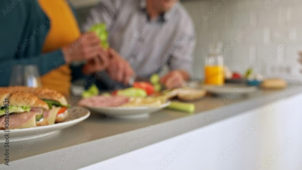 Smiling mixed race family with they son standing in the kitchen preparing sandwich for breakfast at home.