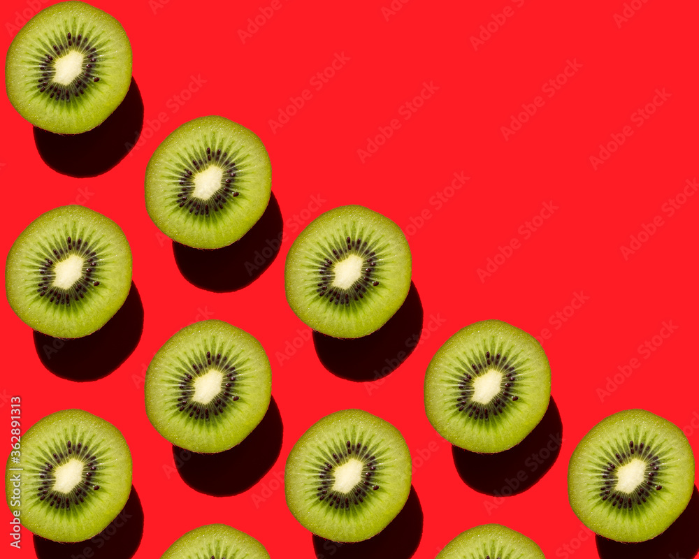 Fototapeta premium Beautiful pattern of kiwi fruit on a red background.