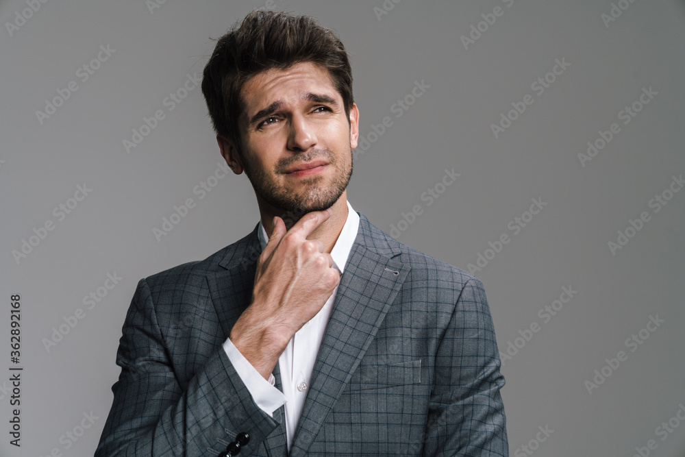 Photo of perplexed young businessman in jacket posing and looking aside Photo of perplexed young businessman in jacket posing and looking aside