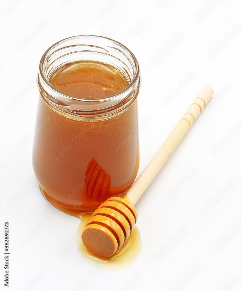 glass jar full of honey and dipper isolated on white background glass jar full of honey and dipper isolated on white background