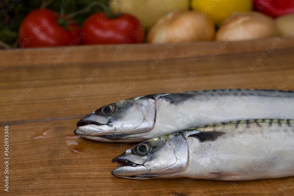 Two whole mackerel fish on a wooden chopping board
Two whole mackerel fish on a wooden chopping board