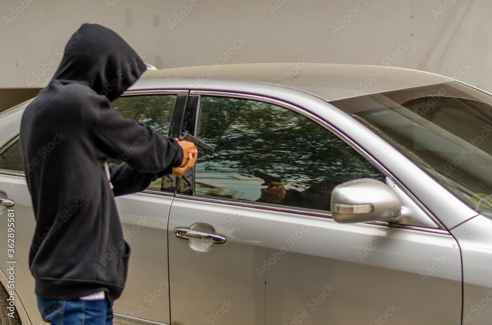 Terrorist or a car thief pointing a gun at the driver - car owner Terrorist or a car thief pointing a gun at the driver - car owner