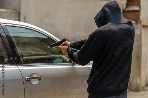 Terrorist or a car thief pointing a gun at the driver - car owner