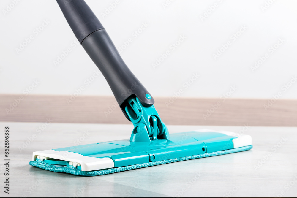 Mopping floor at home or office close-up. Cleaning floor with modern mop.