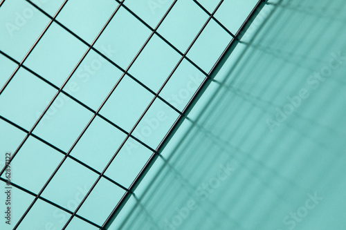 Top view of a metal grid casting shadows on a cyan background