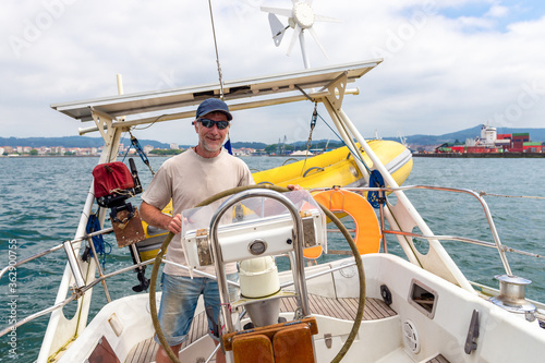 sailor steering sailboat, smiling happy man, sunny day