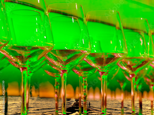  giant wine glasses in a surreal world in a beach at sunset reflect and refract an orange and green light