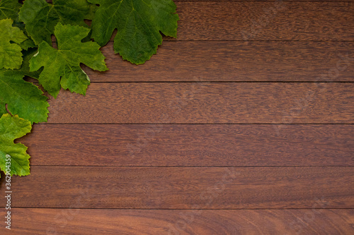 Grape leaves corner border on wooden texture background. Flat lay with empty space for text