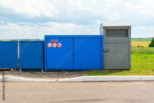 Fenced blue garbage container with fire signs