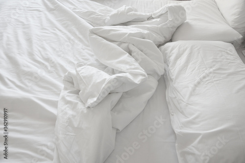 Soft and calm atmosphere image of all white bed room. Pillows and blanket on empty bed, close up. 
