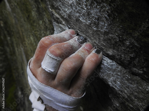 Rock climbers fingers holding on to a crimp on rock, with chalk and tape on hand. High Resolution 