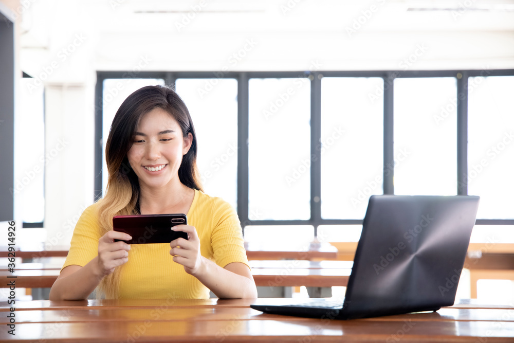 Asian women are using their phone and computer to communicate on the internet. Asian women are using their phone and computer to communicate on the internet.