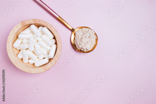 White pills and powder on pink background.