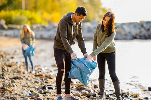 Fotografi Team of environmental conservation volunteers cleaning beach on sunny day