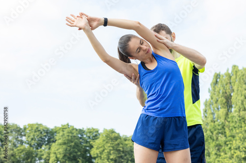 Training with a trainer. A man helps a woman do a workout before playing sports.