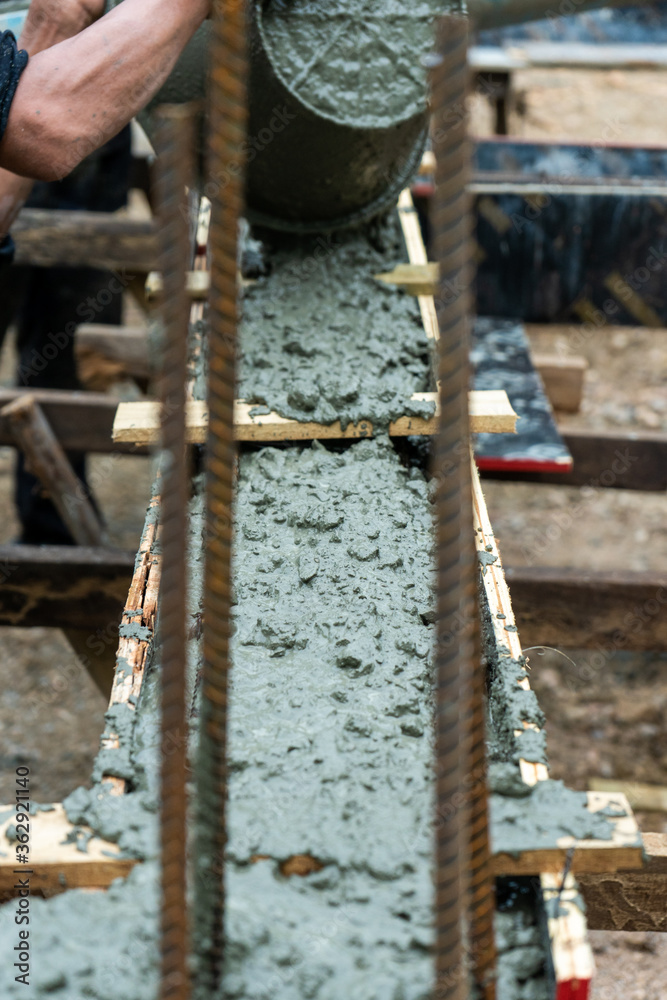 Closeup texture of mixed cement in the wooden mold with motion blurred hand of worker holding dirty bucket in background at the construction site. Closeup texture of mixed cement in the wooden mold with motion blurred hand of worker holding dirty bucket in background at the construction site.